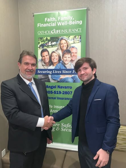 Navarro Insurance Group team members shaking hands in front of a Catholic Life Insurance banner at a community event